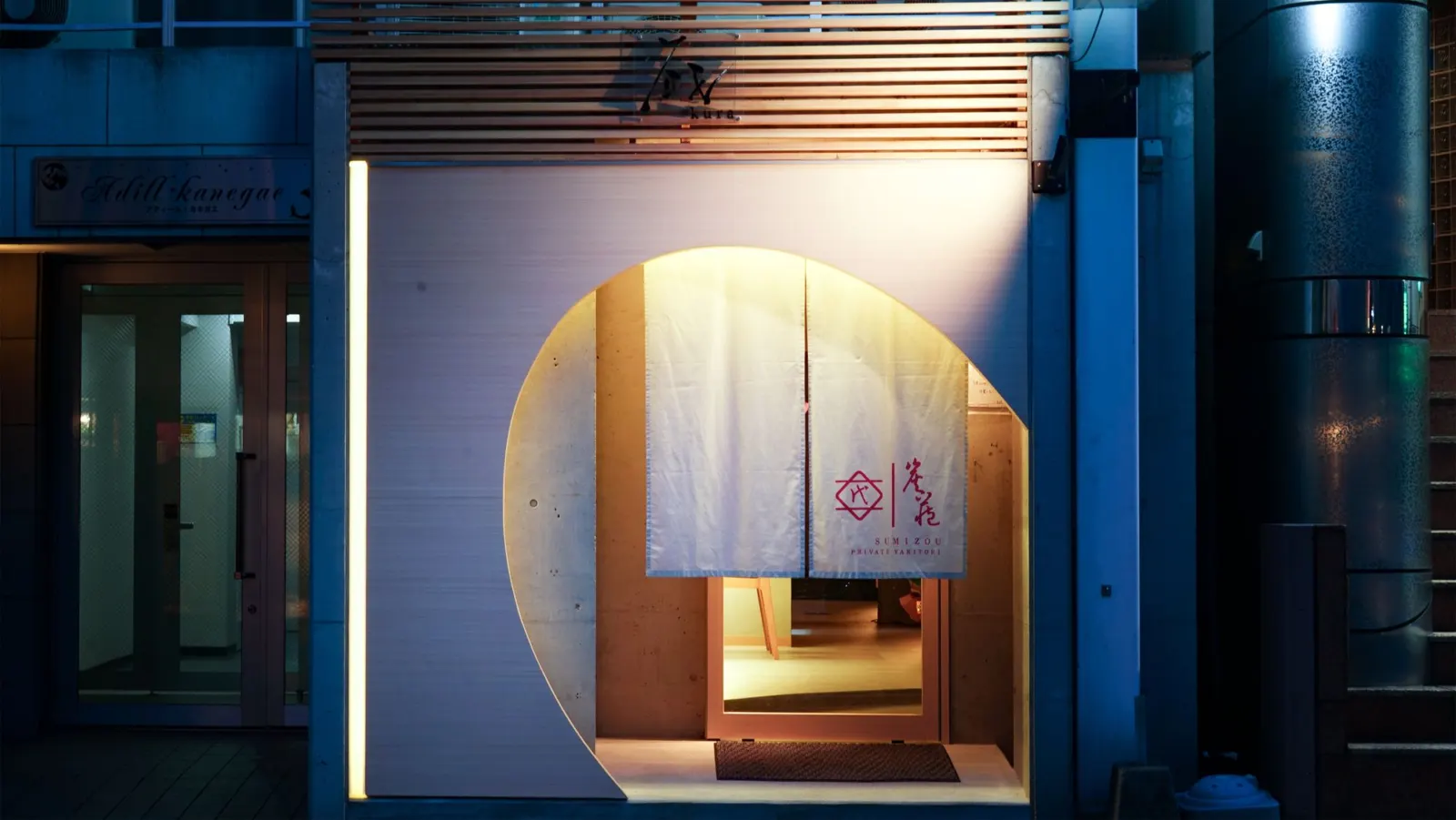丸窓に暖簾が灯る、蔵 -kura- の入口